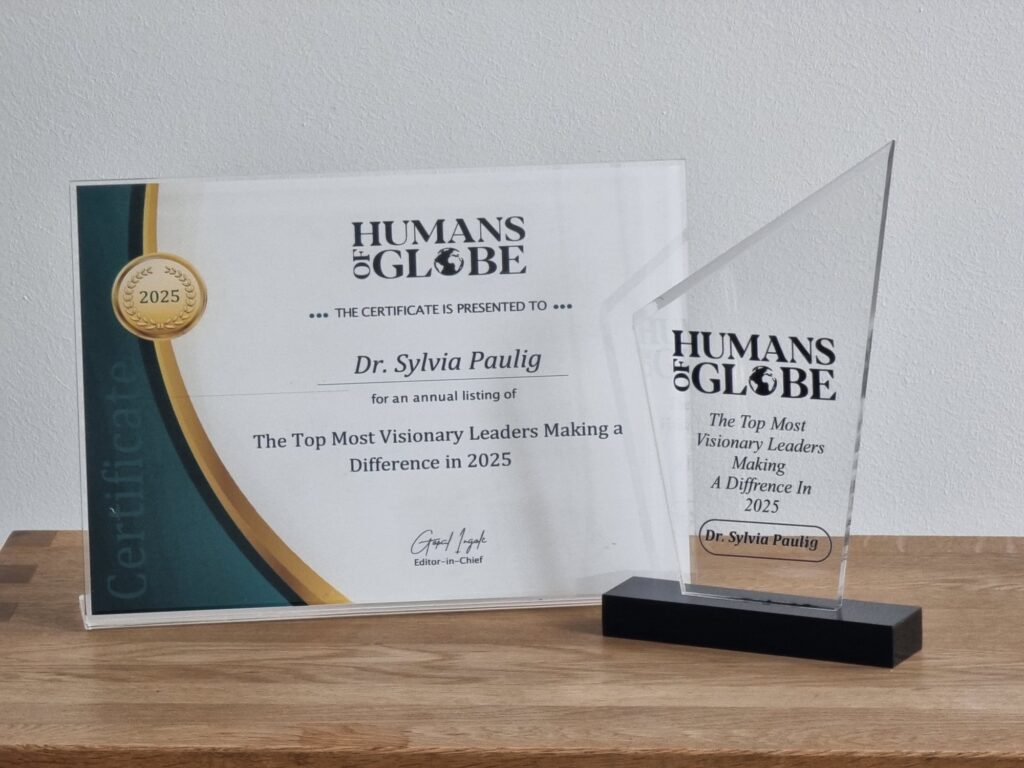 Ein Zertifikat und eine Auszeichnung für Dr. Sylvia Paulig von Humans of Globe auf einem Tisch.