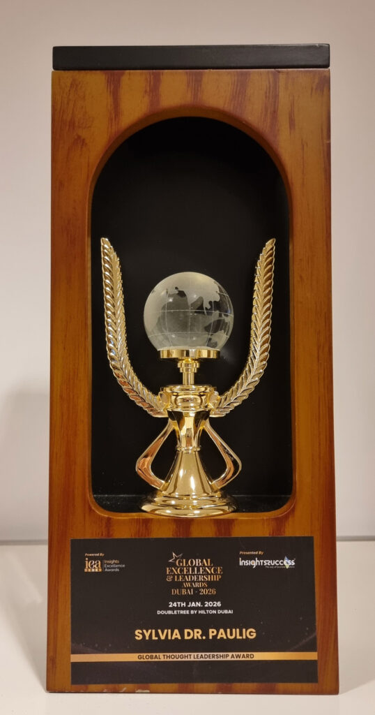 Ein goldener Pokal mit gläserner Weltkugel und Namensschild Sylvia Dr Paulig